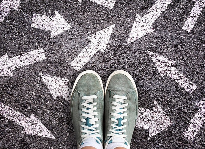 Feet standing on tarmac, surrounded by arrows pointed in various directions.