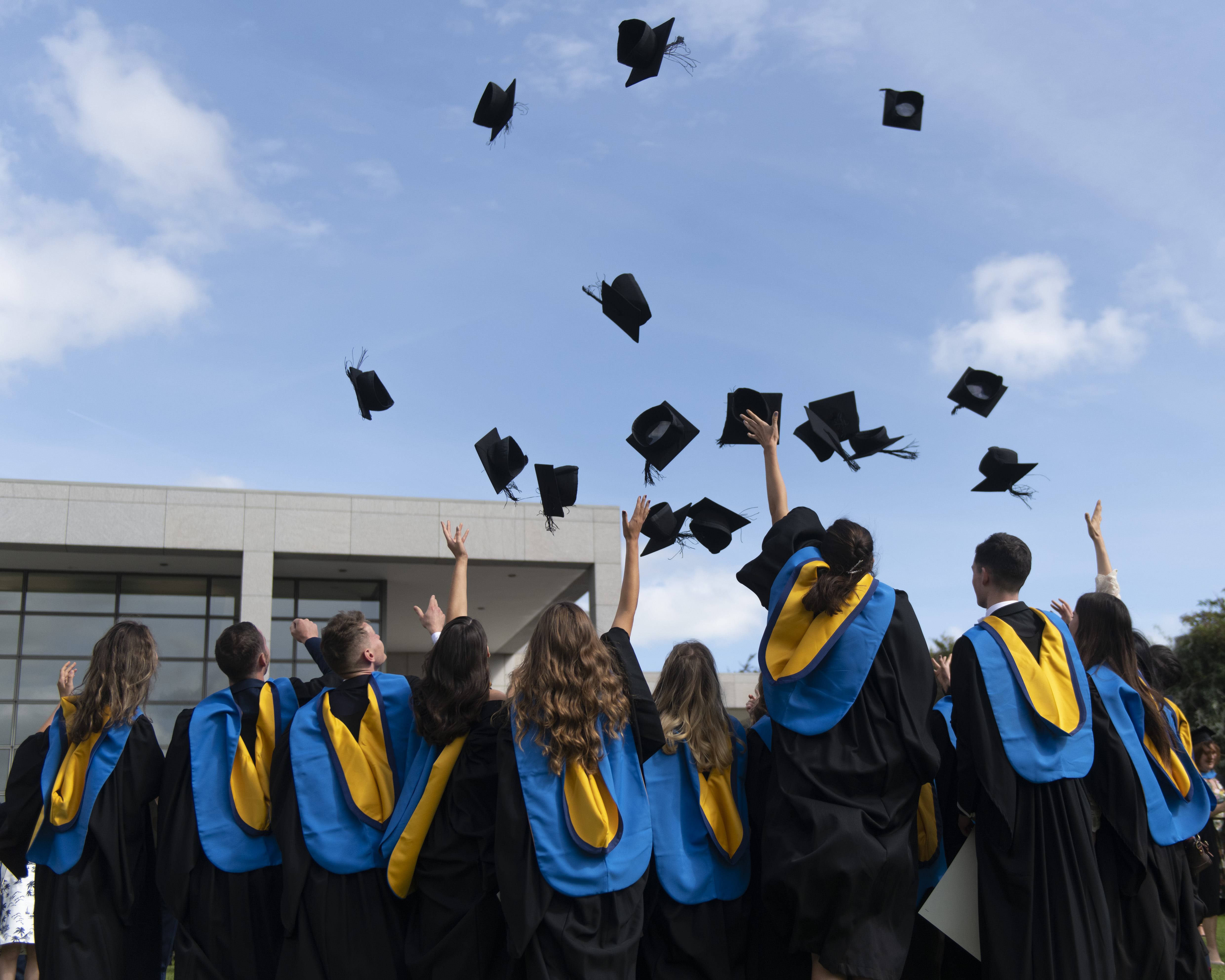 Students in gowns throwing their mortarboards in the air