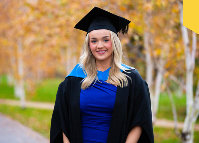 Orlaith Wolohan stands in her cap and gown as graduates from UC