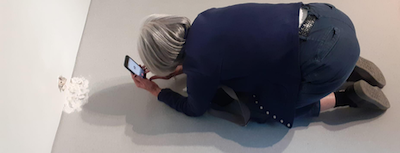 a person crouchedon the ground talking a photo withe their phone