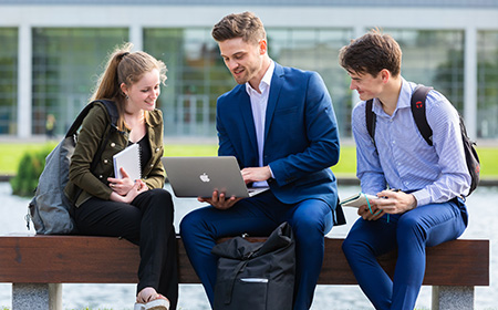 Three people looking at a laptop outdoors on the UCD campus