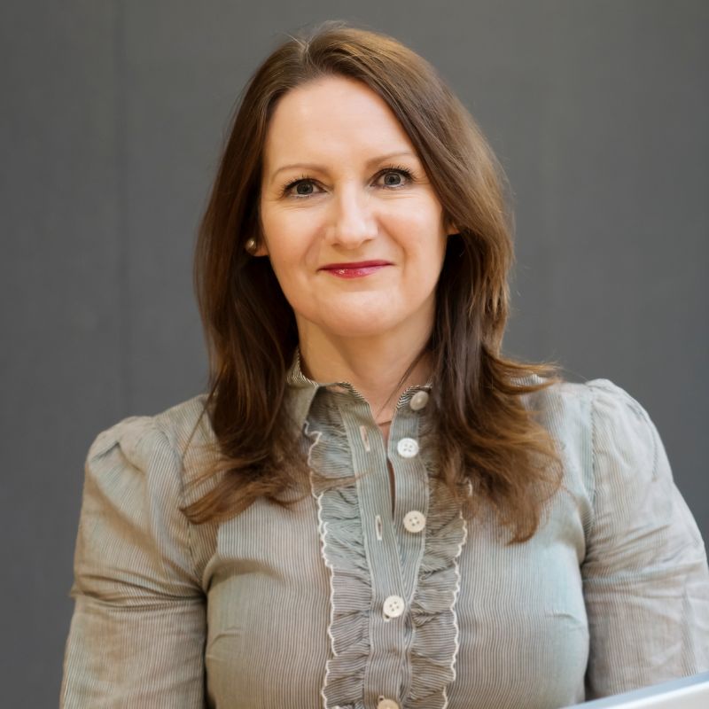 Team member, Fiona stands infront of a blank background