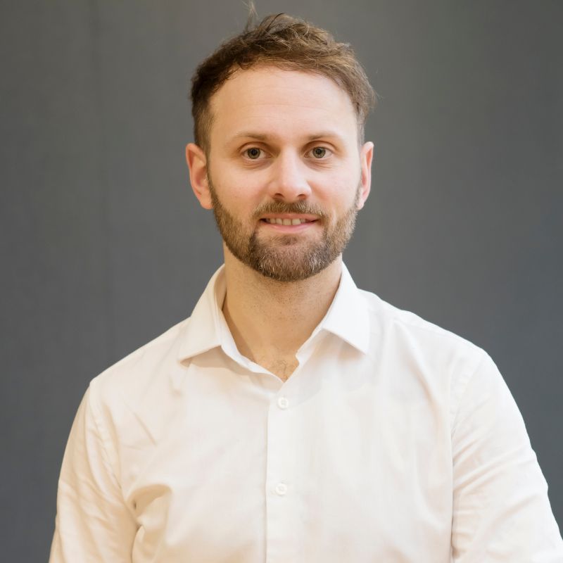 Team member, Simon stands infront of a blank background