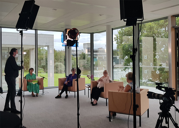 Four women seated for an event with cameras and lighting