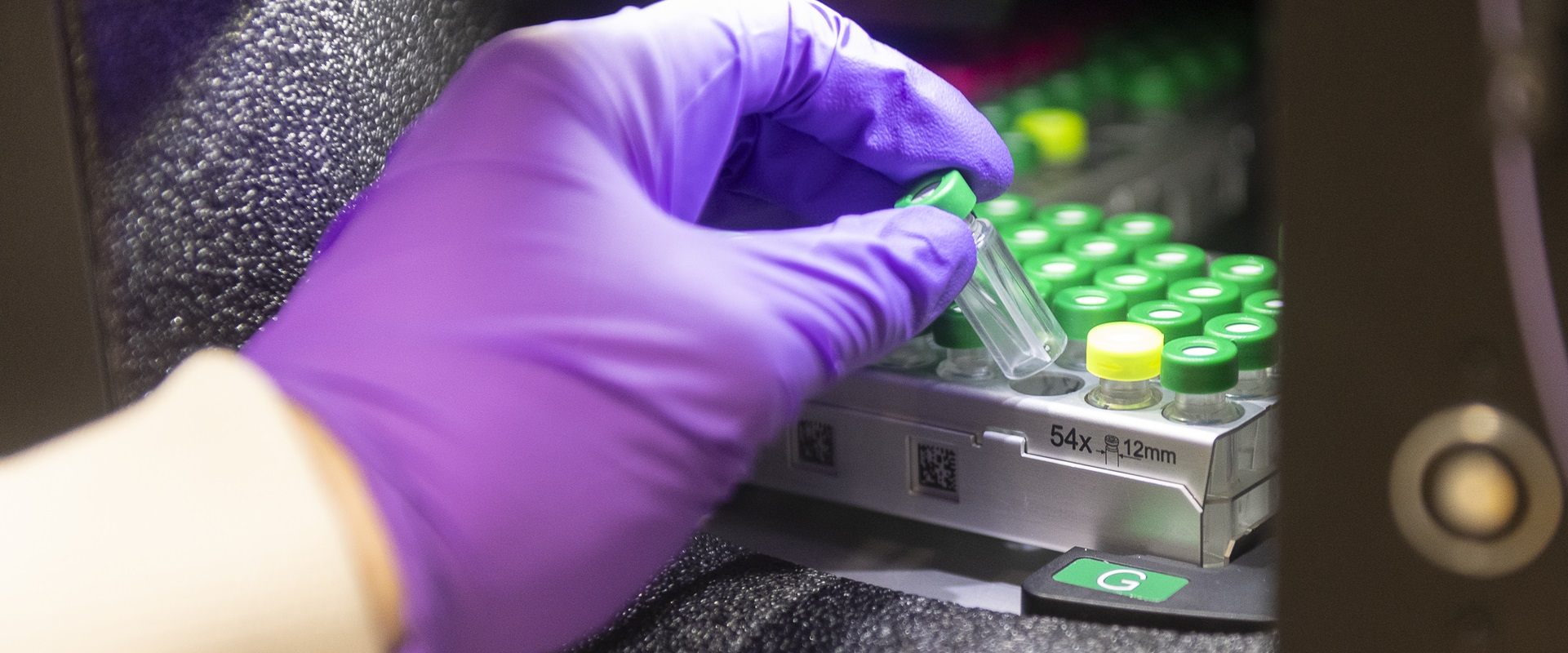 Gloved hand putting tubes in machine