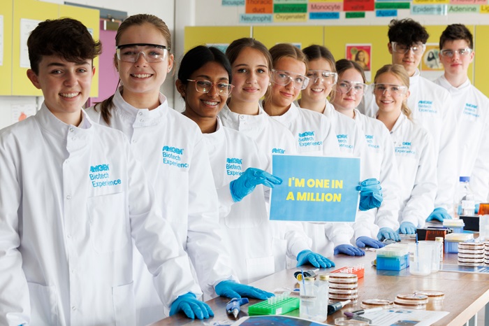 Group of teens in while lab coats smiling