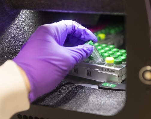 Gloved hand holding tube