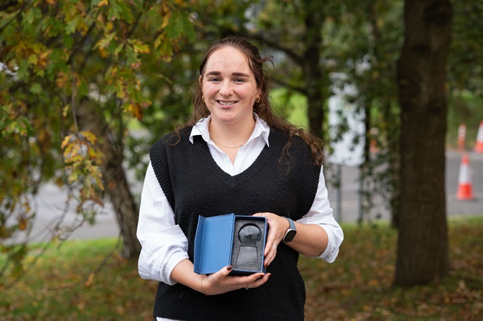 Woman smiling holding a box with glass award inside