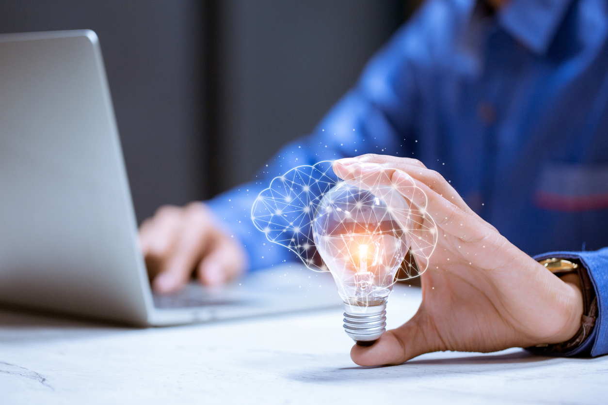 Person on laptop holding lightbulb