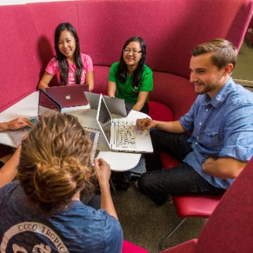 Group of students working together with laptops at a table