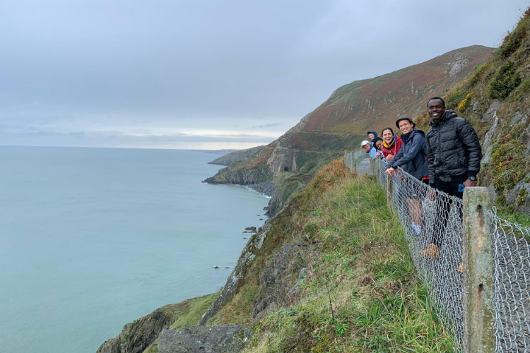 A group of international graduate students studying abroad in Ireland on the Bray cliff walk.