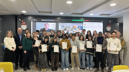 Alt text: A group of students and staff standing together indoors, smiling and holding certificates after completing the UCD Global Big Zero programme.