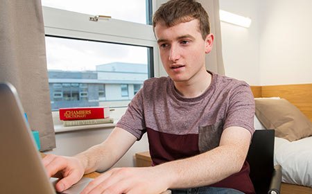 A UCD student studies on his laptop in his UCD dorm room.