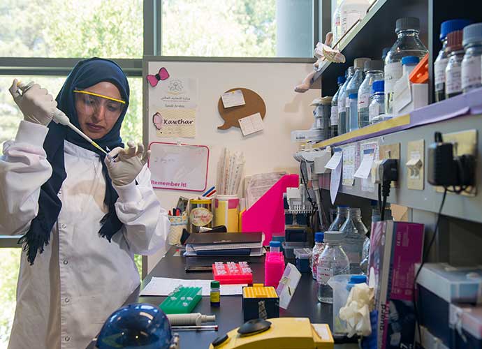 A student uses a pipette to transfer liquid in a laboratory setting.