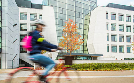 A cyclist with a pink backpack rides past the O’Brien Centre for Science at University College Dublin.