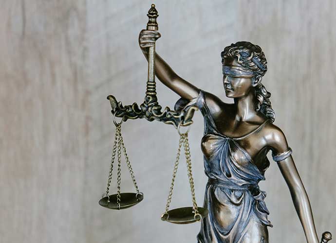 Bronze statue of Lady Justice holding balanced scales in one hand and wearing a blindfold, symbolizing fairness and impartiality.