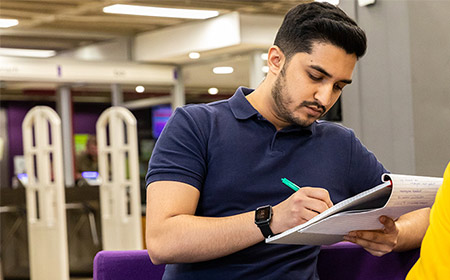 Young main writing with a pen and paper.