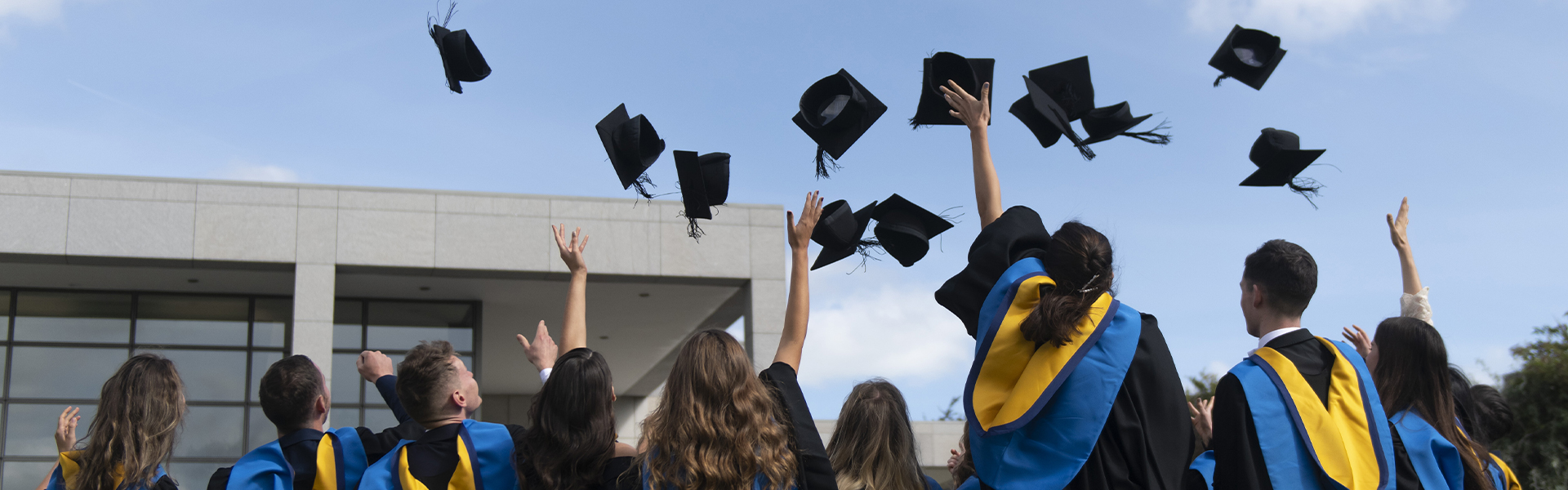 A group of graduates celebrate by throwing their mortarboards into the air.