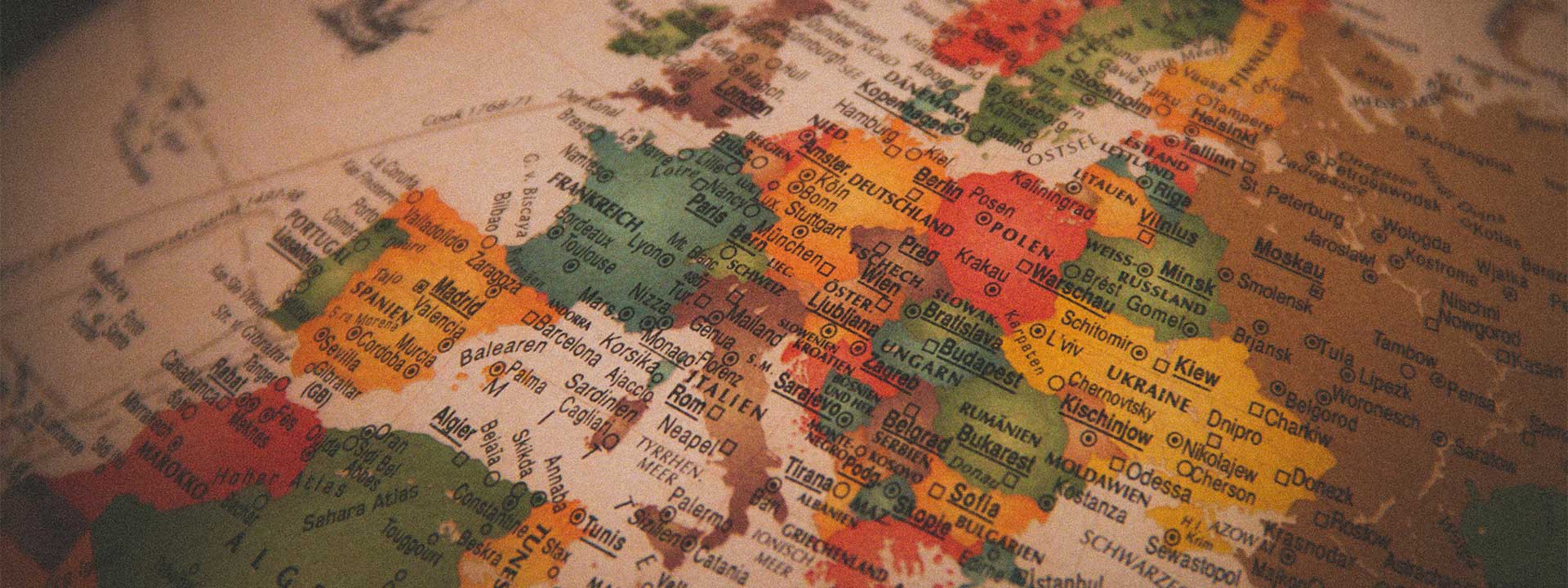 Close-up of a vintage-style map of Europe showing countries including Spain, France, Germany, Italy, Poland, and Ukraine, with major cities like Madrid, Paris, Berlin, Rome, and Warsaw labeled.