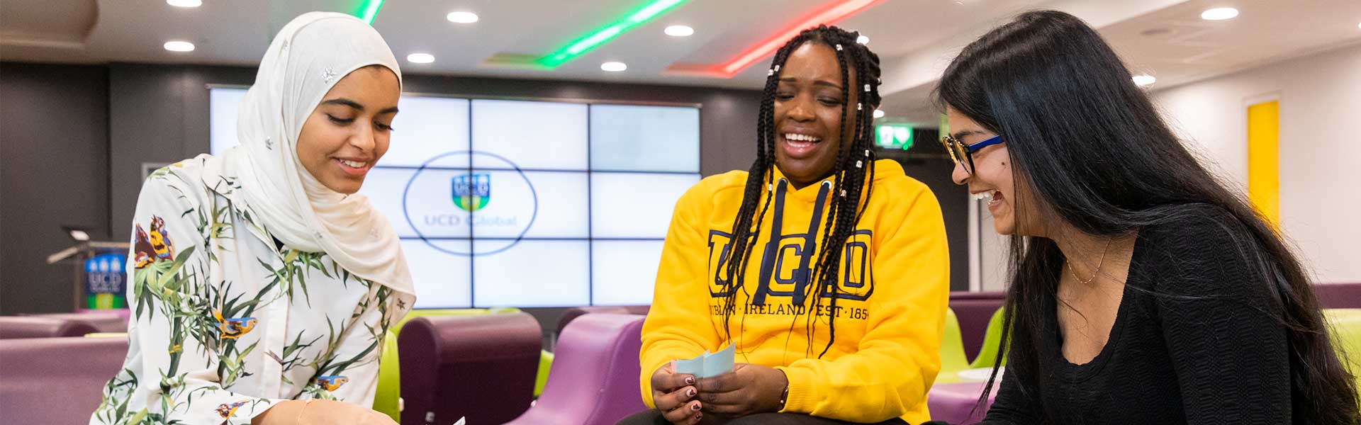 Three students laugh around a board game.
