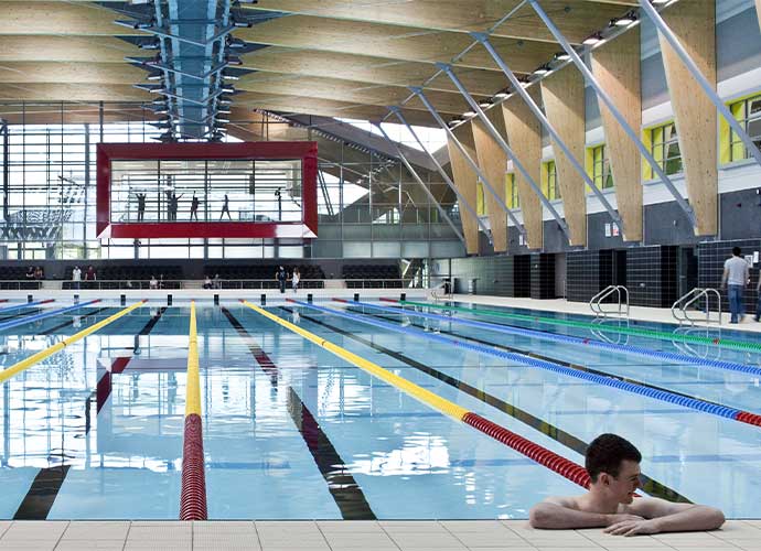 A swimmer takes a rest at the end of a large swimming pool.