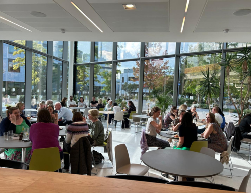 Group of staff at event in UCD University Club, glass walls and greenery