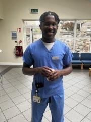 Man in scrubs in hospital smiling at camera