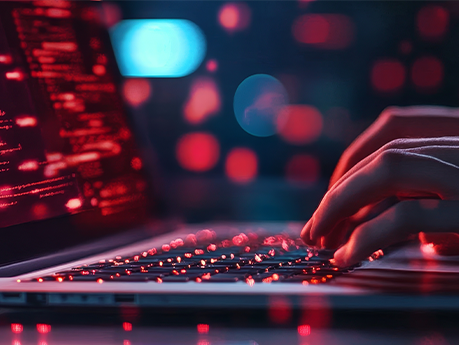 A close-up of a person's hands typing on a laptop keyboard, the screen is illuminated with red code. The image symbolizes ethical hacking, cybersecurity, digital security, data protection, and online