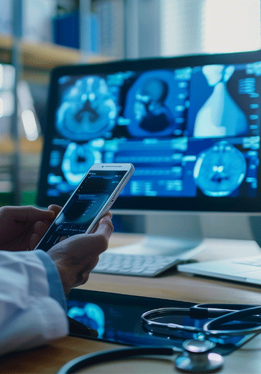 A male doctor in a white coat analyzes medical data on a smartphone while reviewing scan images on multiple computer screens in a bright office.