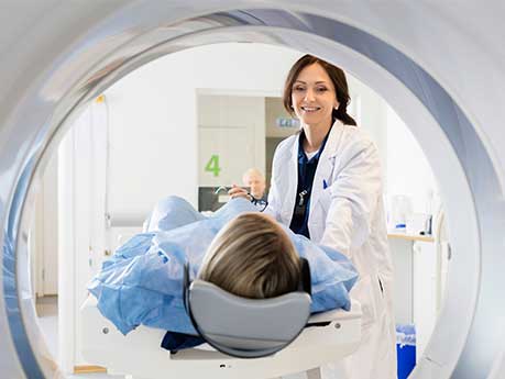 Woman standing over a CT scan.