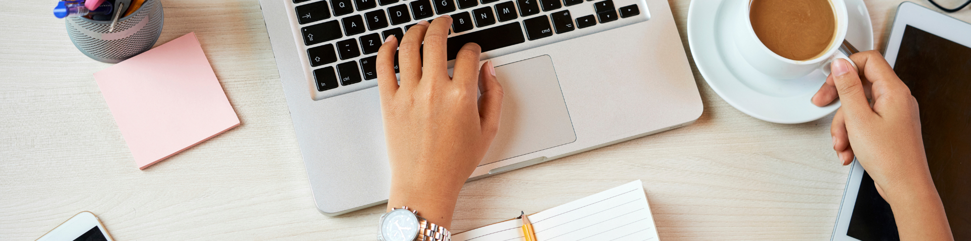 Hand on keyboard with cup of coffee to the side