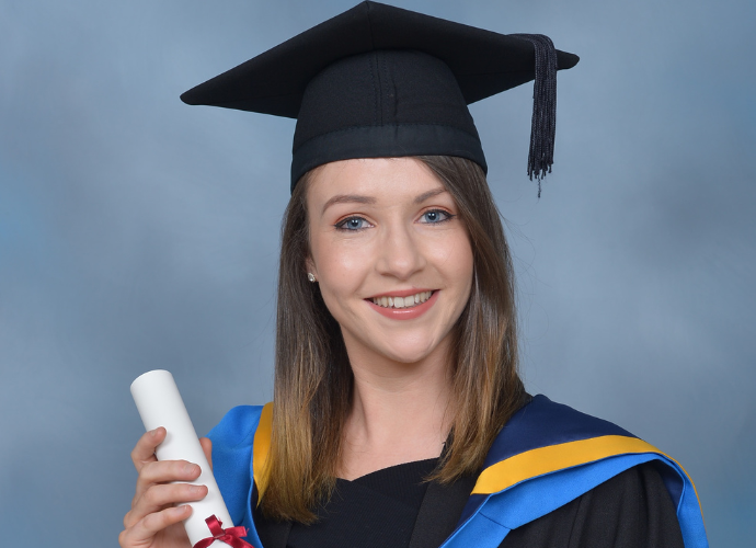 Female graduate in cap and gown holding a scroll