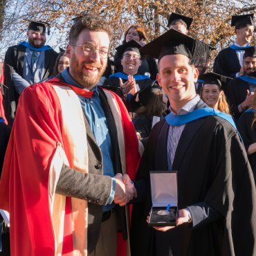 A UCD graduate receiving a medal from a UCD academic.