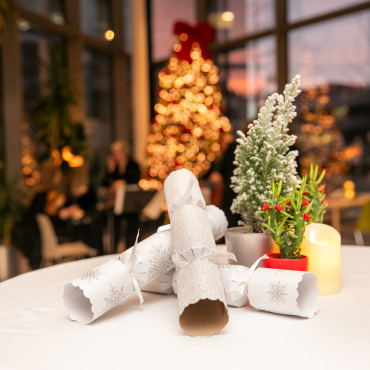 Christmas crackers on a table in front of a Christmas tree at the UCD Physiotherapy 70th anniversary celebration
