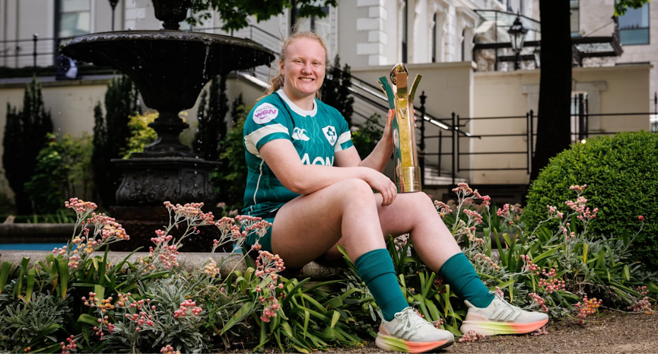Aoife Wafer rugby player sitting on side of fountain holding Player of Championship trophy