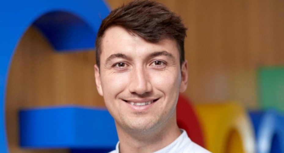 Man with dark hair smiling to camera