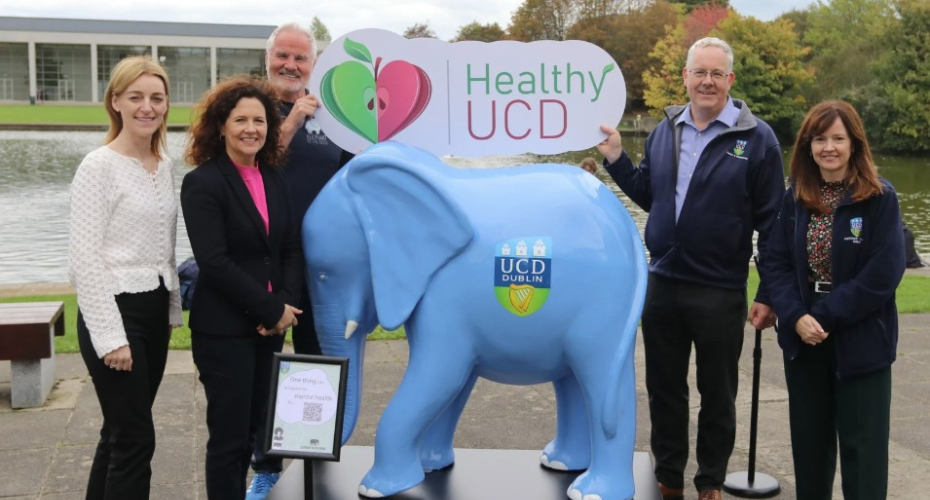 Group of people standing beside a blue model elephant in front of UCD lake