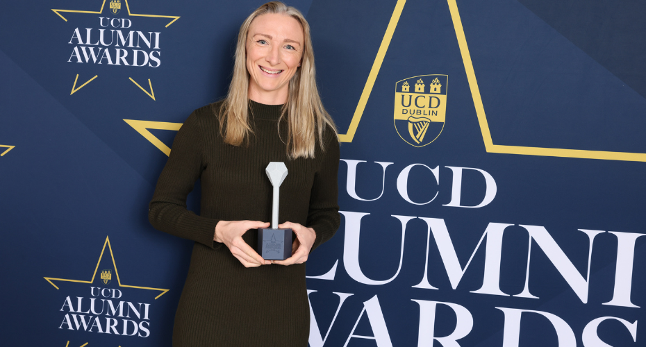 A woman with blonde hair holding an award in front of a navy backdrop