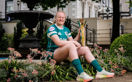 Aoife Wafer rugby player sitting on wall holding Player of Championship trophy