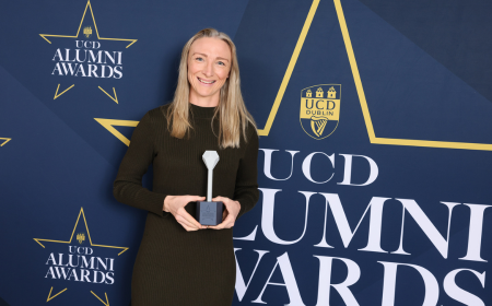 A woman with blonde hair holding an award in front of a navy backdrop