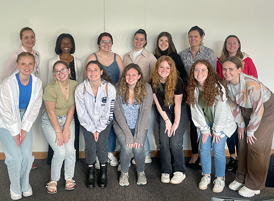 Penn State students standing in tow rows in front of a wall looking at camera