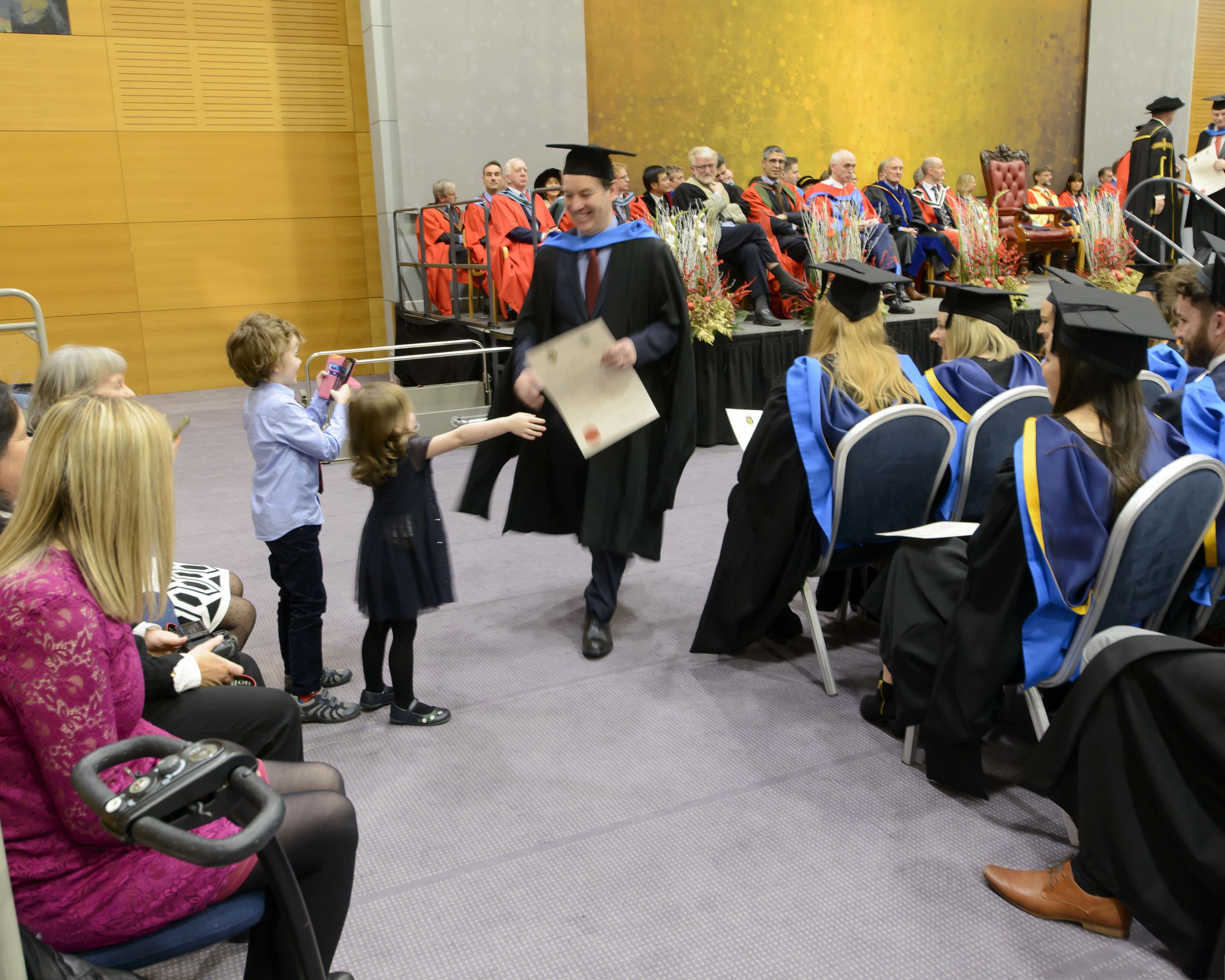 A student who graduated being greeted by two children-decorative