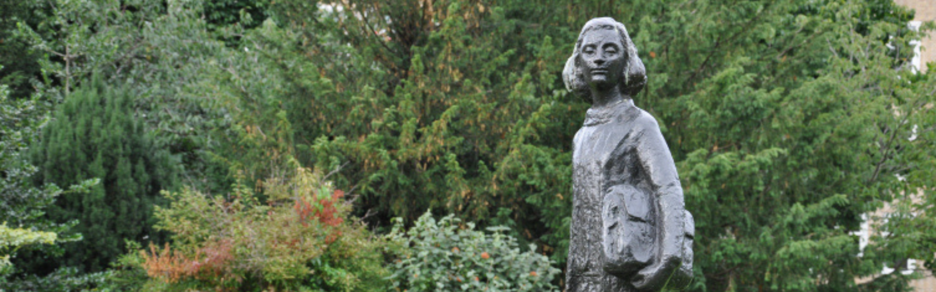 Statue of Anne Frank in front of trees