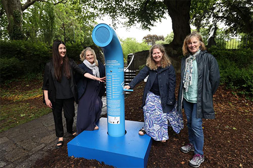 A group of poets standing beside a blue poetry jukebox