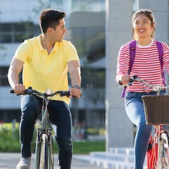 A man and a woman ride their bikes through UCD Campus