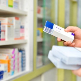 A pharmacist hands over medicine to a customer in a pharmacy