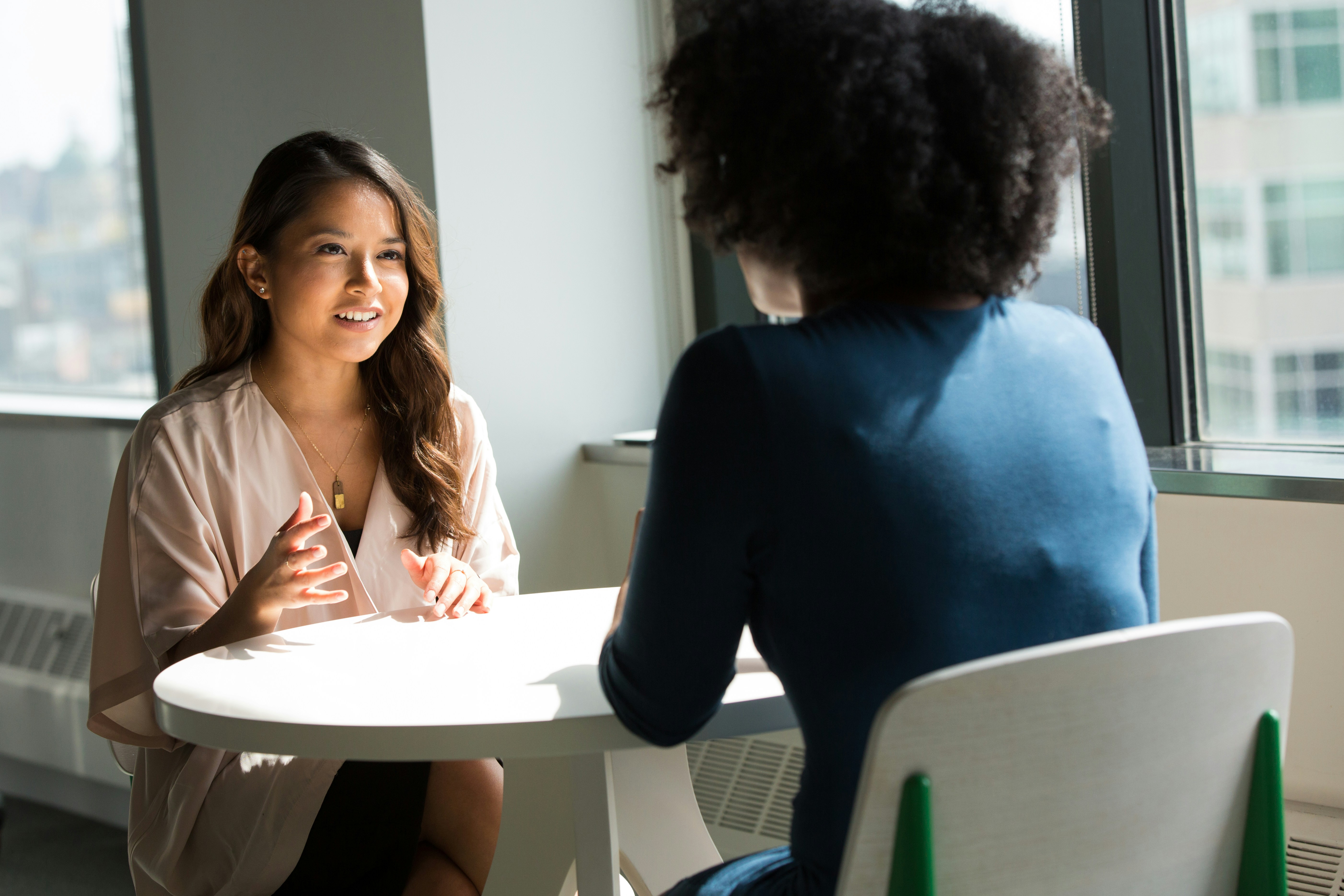 Two women sitting at a table, having a discussion