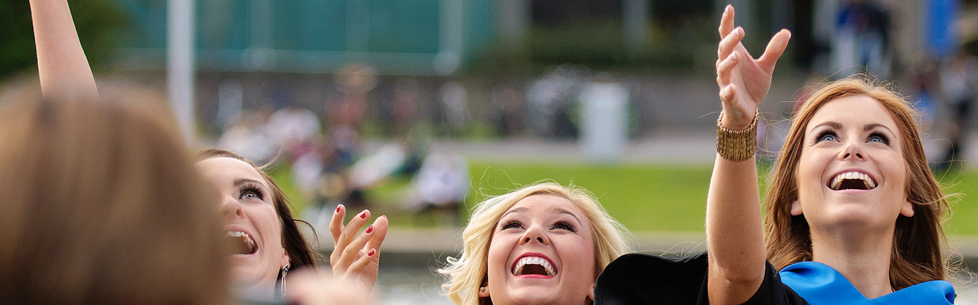 A group of students throw their mortarboard caps in the air.