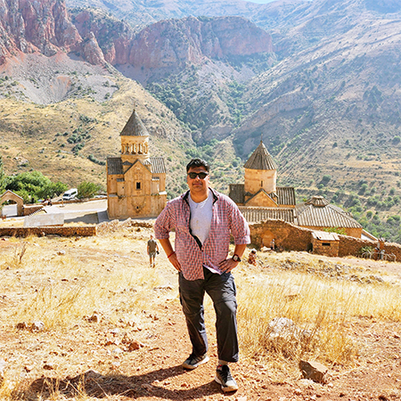 Dr Sourav Bhattacharjee standing on a hill with old religious buildings in the background