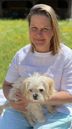 Robin Farrell sitting on grass with her dog on her lap